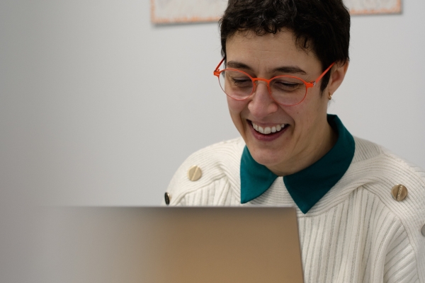 Portrait de Sylbohec, artiste photographe, souriante devant son ordinateur